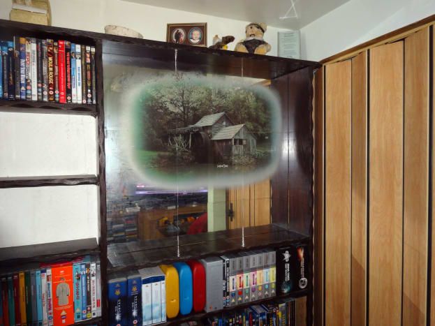 DVD y discos Blu-ray retirados del área donde estaría trabajando para colocar los nuevos estantes; revelando la imagen decorativa espejada detrás.