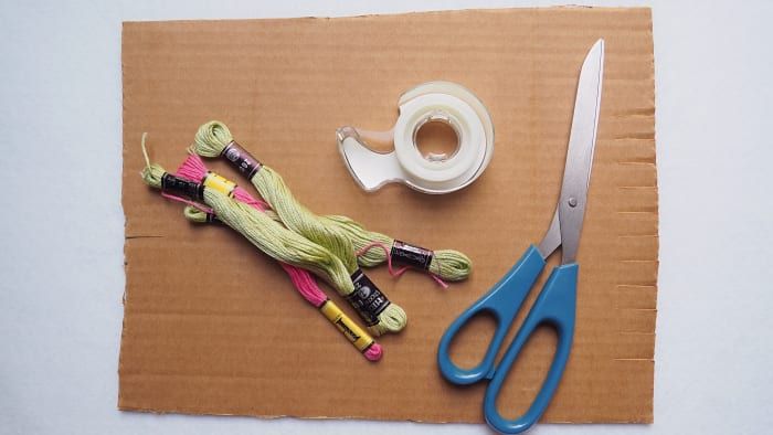 Necesitará hilo de bordar, tijeras, cinta adhesiva y cartón (para hacer un telar).