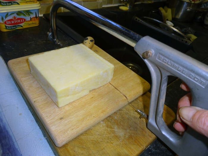 Schneiden von Käse mit einer Bügelsäge mit Käsedraht.