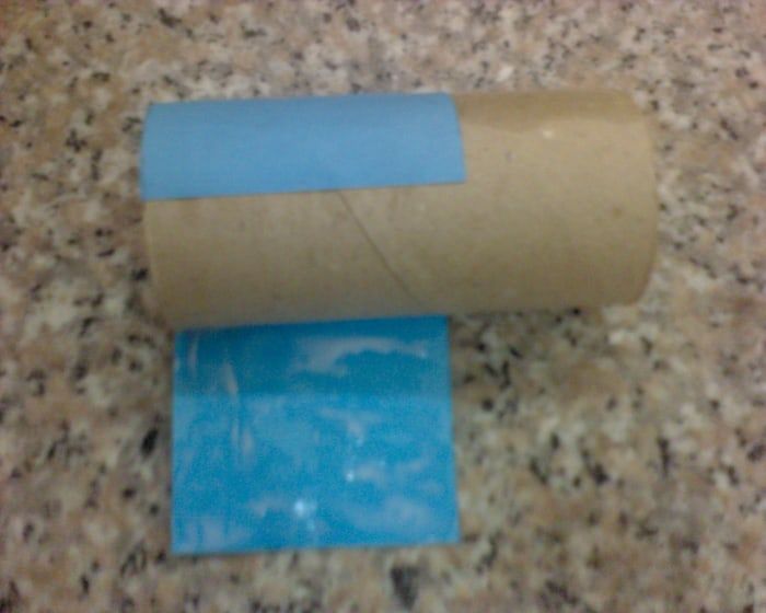 Pega el papel azul alrededor del rollo de papel higiénico.