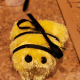 Owiń czarną wstążkę wokół pszczoły, zawiązując u góry kokardkę, aby utworzyć paski.