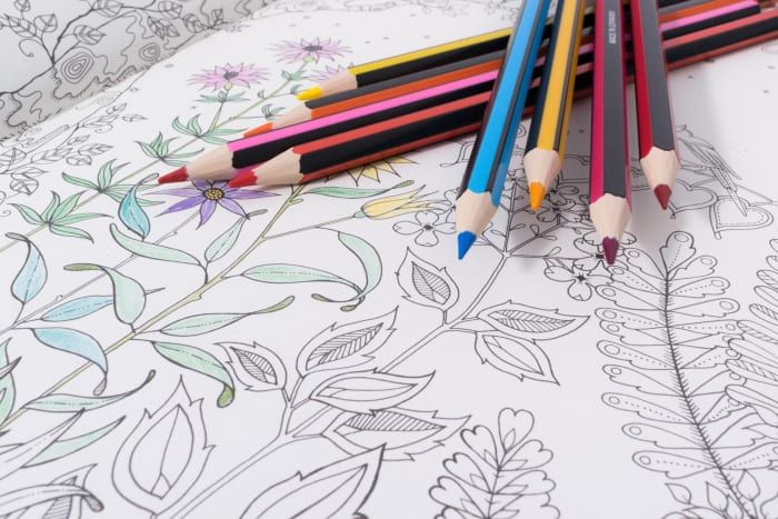 Une variété de crayons de couleur a été sélectionnée pour commencer à colorier cette esquisse géométrique de fleurs.