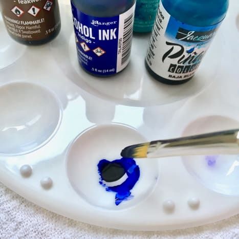 Mezcla de colores de tinta en una pequeña paleta de pintura plástica con un pincel.