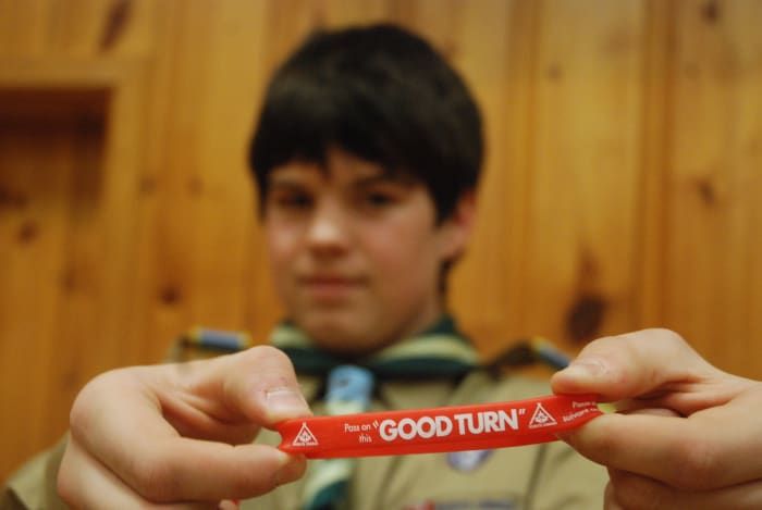 Un Scout muestra un brazalete para promover la Semana del Buen Turno, un momento en el que la organización retribuye a la comunidad.