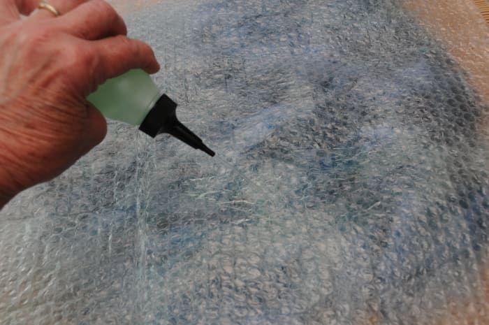 Benetzen Sie die Oberfläche der Luftpolsterfolie mit warmem Seifenwasser, um das einfache Reiben der Finger auf der Oberfläche zu erleichtern.