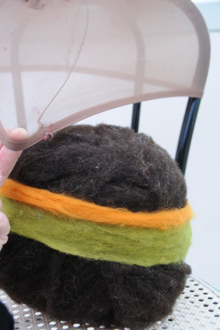 Coloque la bola cubierta de lana en una silla como se muestra y levántela dentro de la media como se muestra.