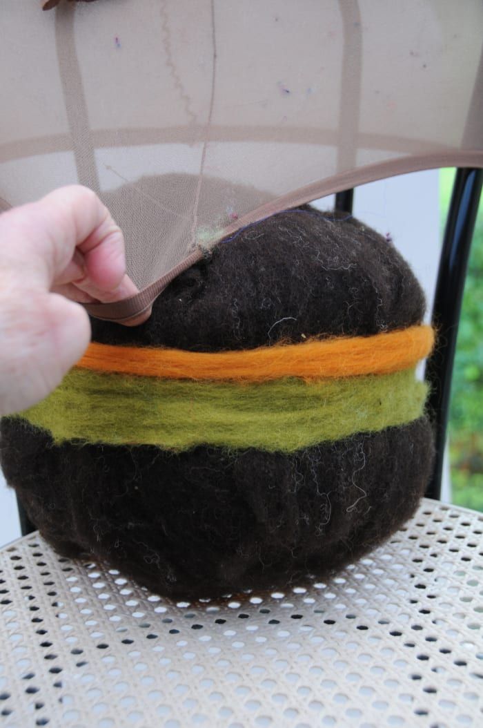 Poner la bola cubierta de lana en un par de medias cortadas