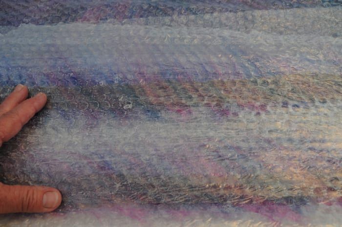 Dé la vuelta a los bordes de la mecha de lana para formar un borde ordenado sobre las tiras de seda.