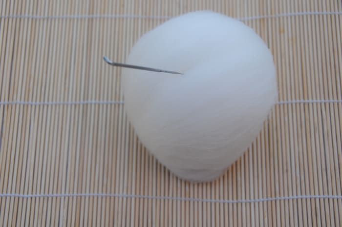 Glätten Sie die Wolle und den Nadelfilz, gerade genug, um die Form des Balls beizubehalten.
