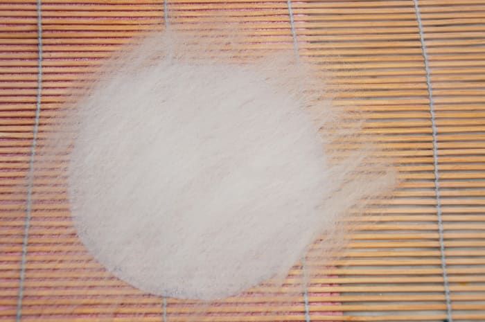 Schablone mit einer dünnen, gleichmäßigen Schicht weißer Fasern bedeckt.