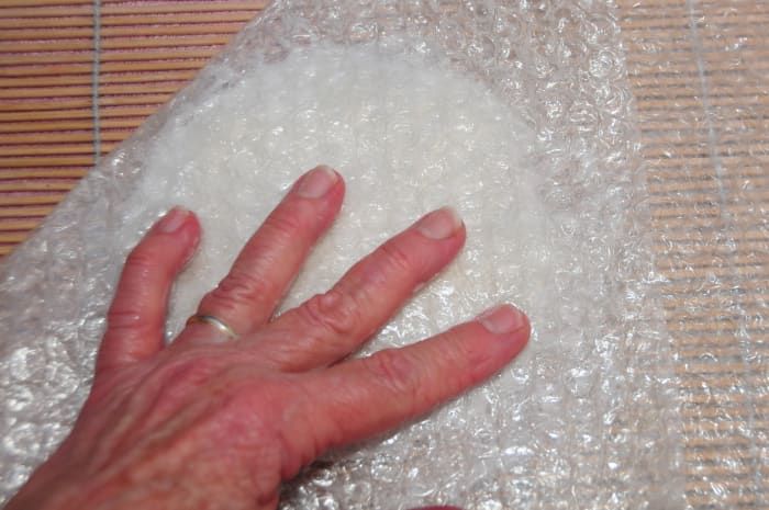 Frote las fibras húmedas debajo del plástico de burbujas hasta que se aplanen.