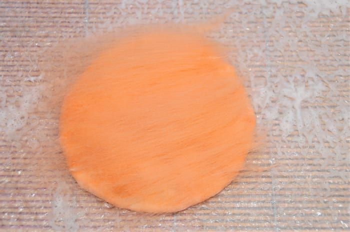 Decken Sie die 2. Seite der Schablone mit einer dünnen Schicht orangefarbener Merinowolle ab.