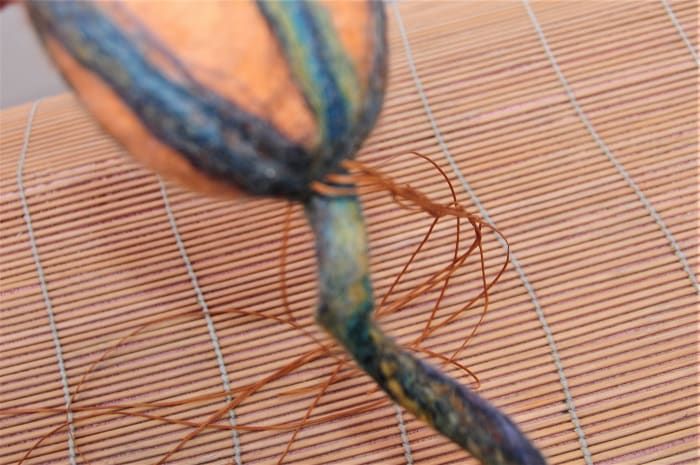 Coser hilos con la aguja de muñeca para formar las secciones de calabaza.