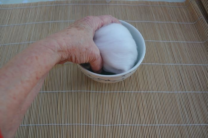 Befeuchten Sie alle Seiten der mit Wolle bedeckten Polystyrolkugel, indem Sie jede Seite leicht in das heiße Seifenwasser tauchen.