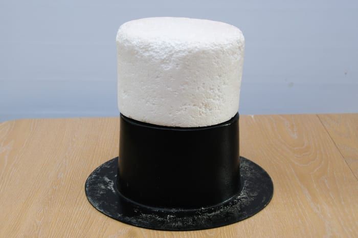 El bloque del sombrero de poliestireno se balanceó sobre el moldeador del sombrero. Esto se usó dentro de la funda de la papelera para aumentar la altura del sombrero.