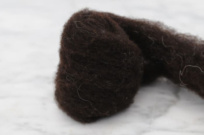 Envuelva la lana alrededor del nudo para formar una bola del tamaño de un puño.